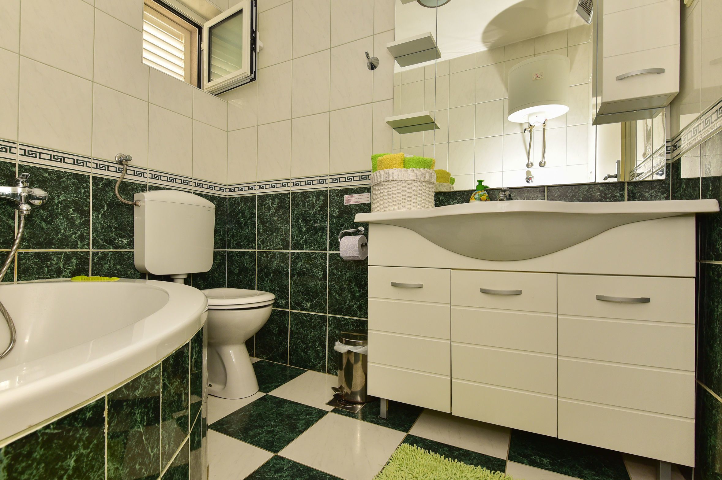 A bathroom with a white sink, toilet, and vanity with drawers.