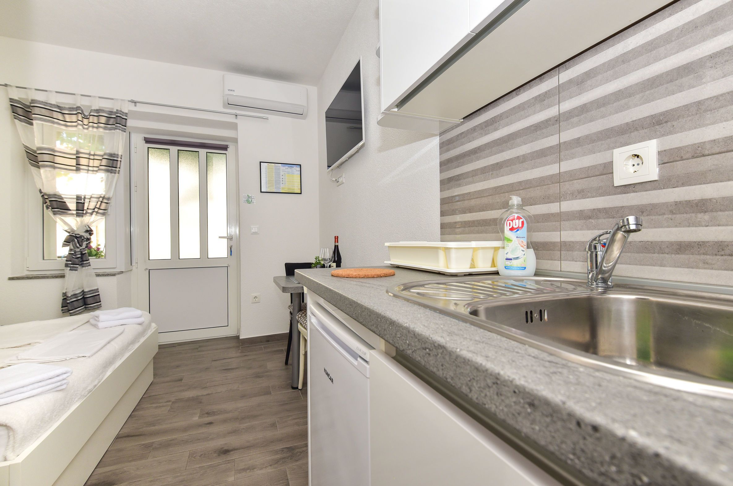 A modern kitchen with a granite countertop, stainless steel sink, and a dishwasher.