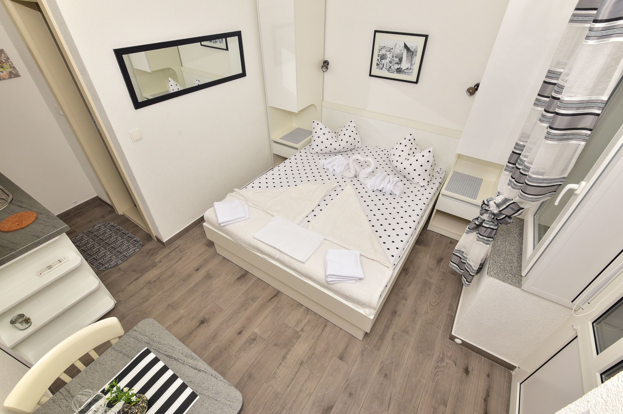 A neatly arranged bedroom with a bed, bedside tables, a mirror, and a wardrobe.