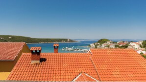 A coastal town with terracotta-roofed buildings, a marina, and a clear blue sky. - Apartment Anica (Kampor)