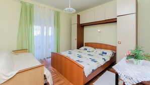 A bedroom with a wooden bed, a desk, a chair, a ceiling fan, and a window with curtains. - Apartment Anica (Kampor)