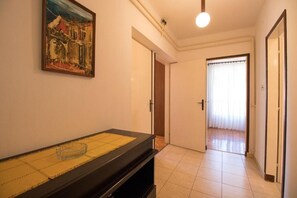 A hallway with a black console table, a painting on the wall, and a door leading to another room.