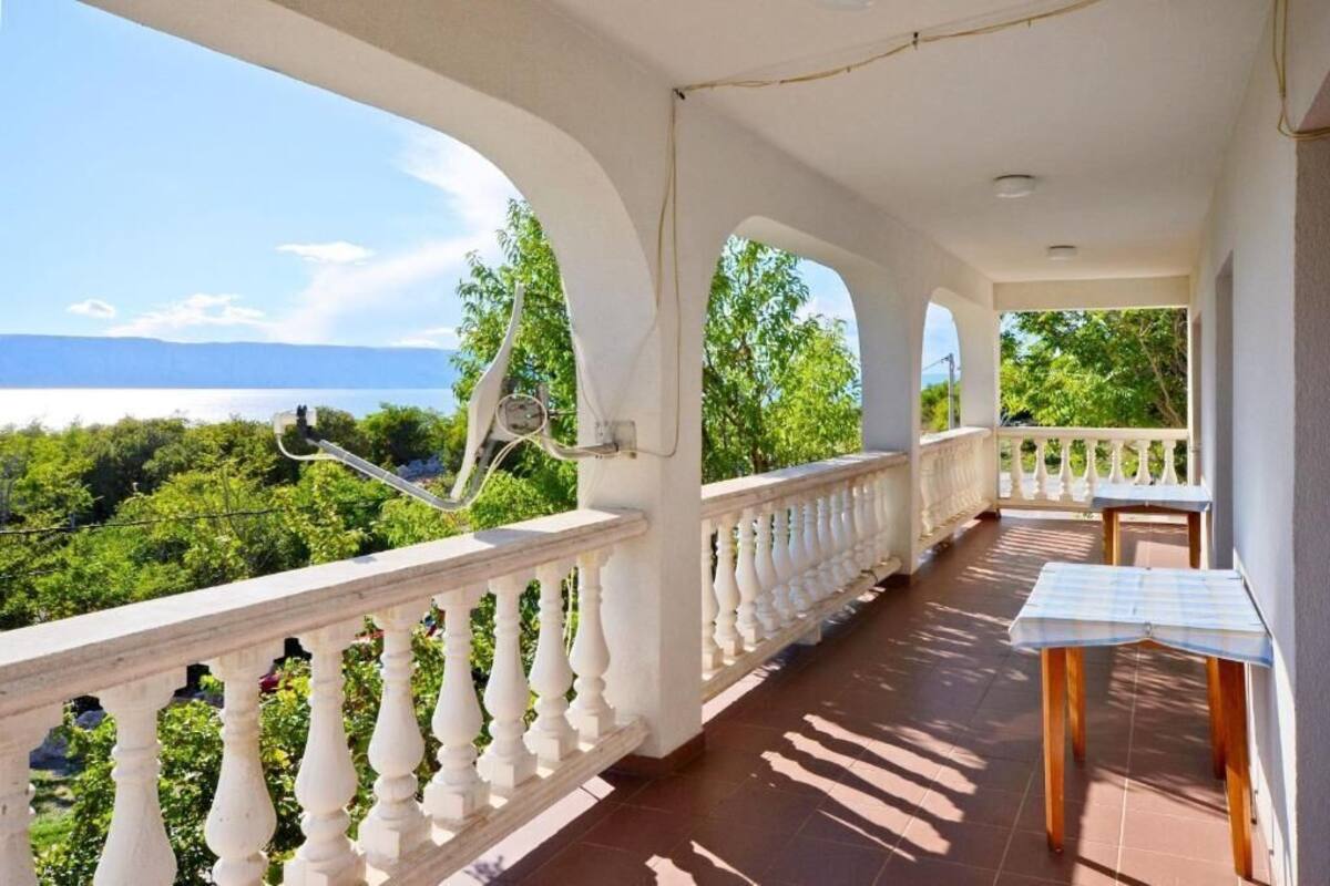 A balcony with a view of a green landscape and a body of water.
