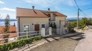 A two-story house with a tiled roof, a front door, and a staircase leading to the upper floor. - Apartments Bozana (Dramalj)