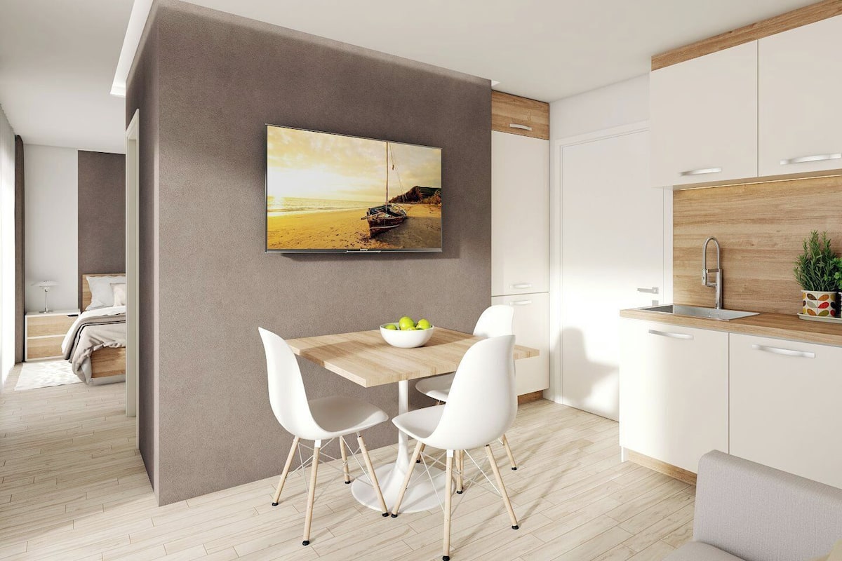 A modern kitchen with a wooden countertop, white cabinets, and a painting of a beach scene.
