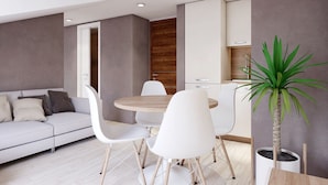 A modern living room with a sofa, white chairs, a round table, and a potted plant. - Apartments Villa Subic (Kampor)