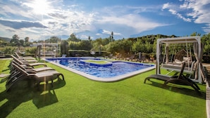 A pool area with artificial grass, lounge chairs, and a swing chair. - Apartments Villa Subic (Kampor)