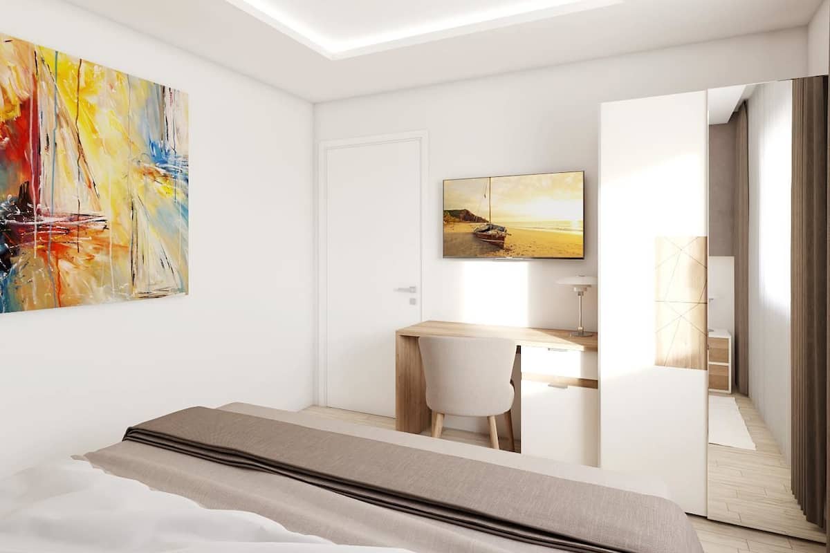 A modern bedroom with a bed, a desk, and a chair. There is a painting on the wall and a window providing natural light.