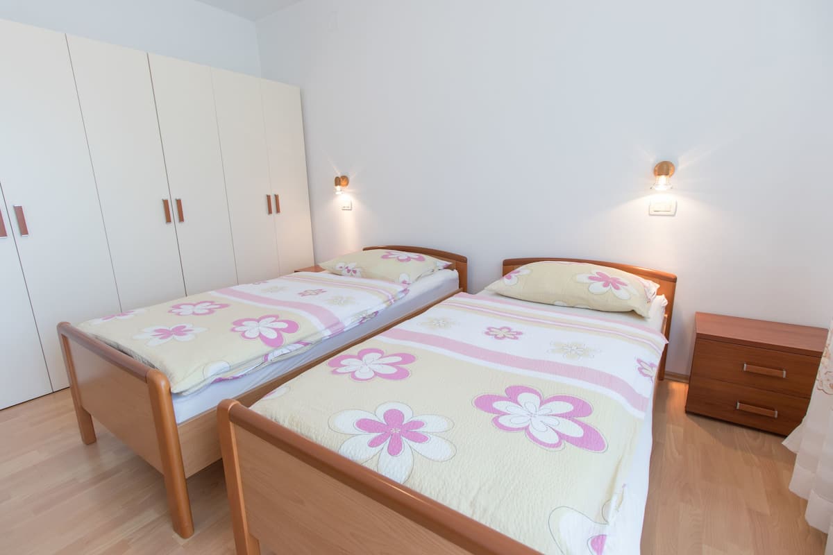 A bedroom with two single beds, a wardrobe, and a nightstand.