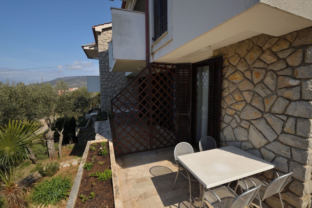 A stone house with a patio, outdoor seating, and a view of the surrounding landscape.