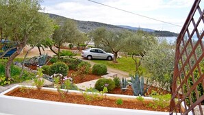 A garden with various plants and a parked car. - Apartments Marija (Cres)