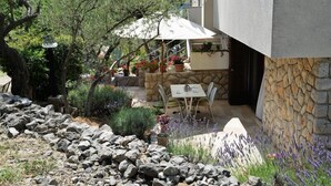 A patio area with a table and chairs, surrounded by potted plants and a stone wall. - Apartments Marija (Cres)