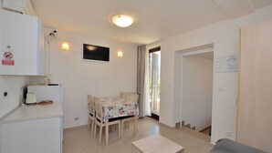 A compact living space with a dining area, a small kitchenette, and a sofa. - Apartments Marija (Cres)