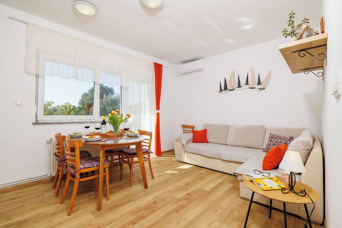 A dining area with a wooden table and chairs, a sofa, and a small side table with a lamp.