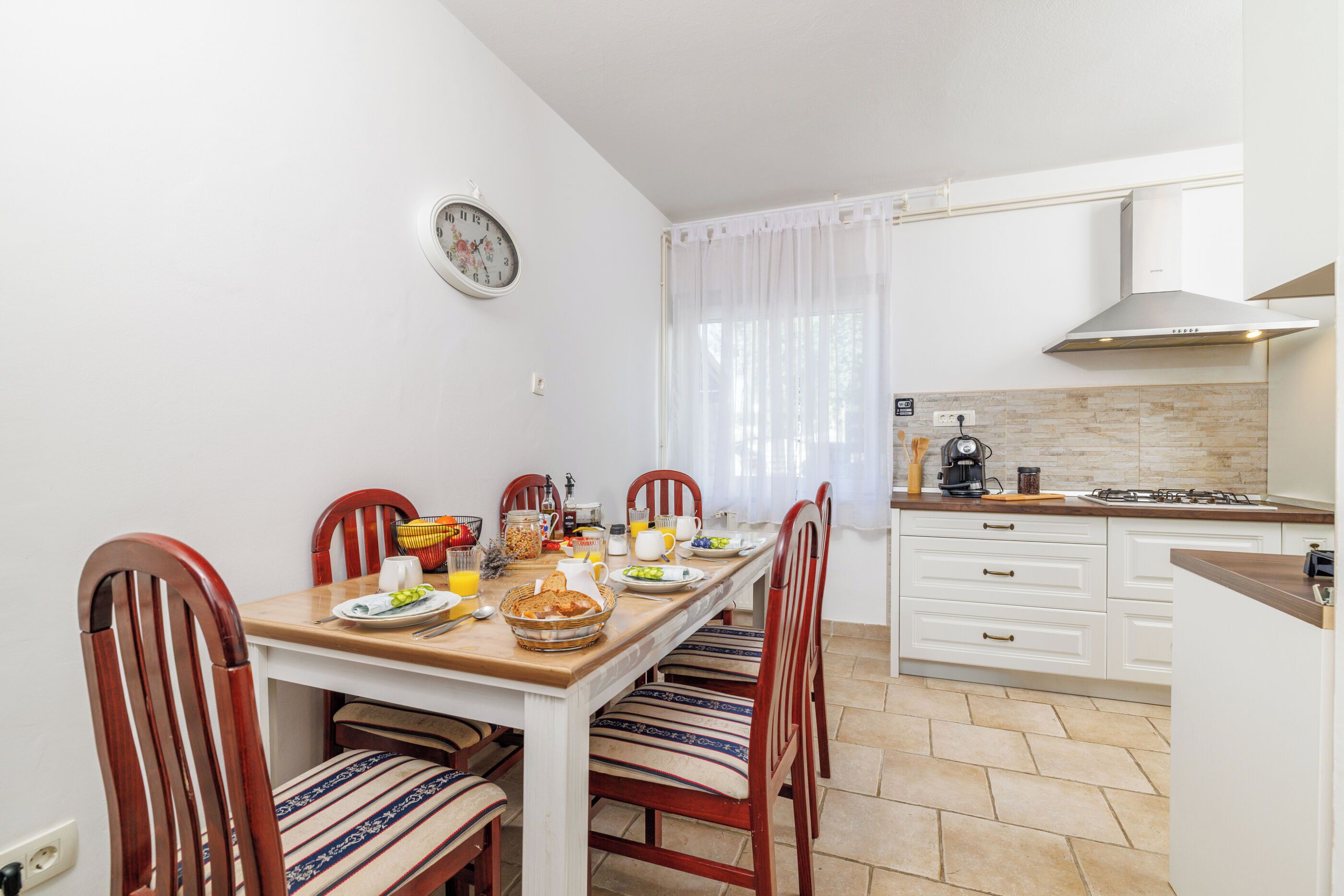 A dining area with a wooden table, chairs, and a kitchen in the background.