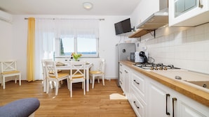 A modern kitchen with white cabinetry, a wooden countertop, and a built-in stove. - Apartments Iva (Crikvenica)