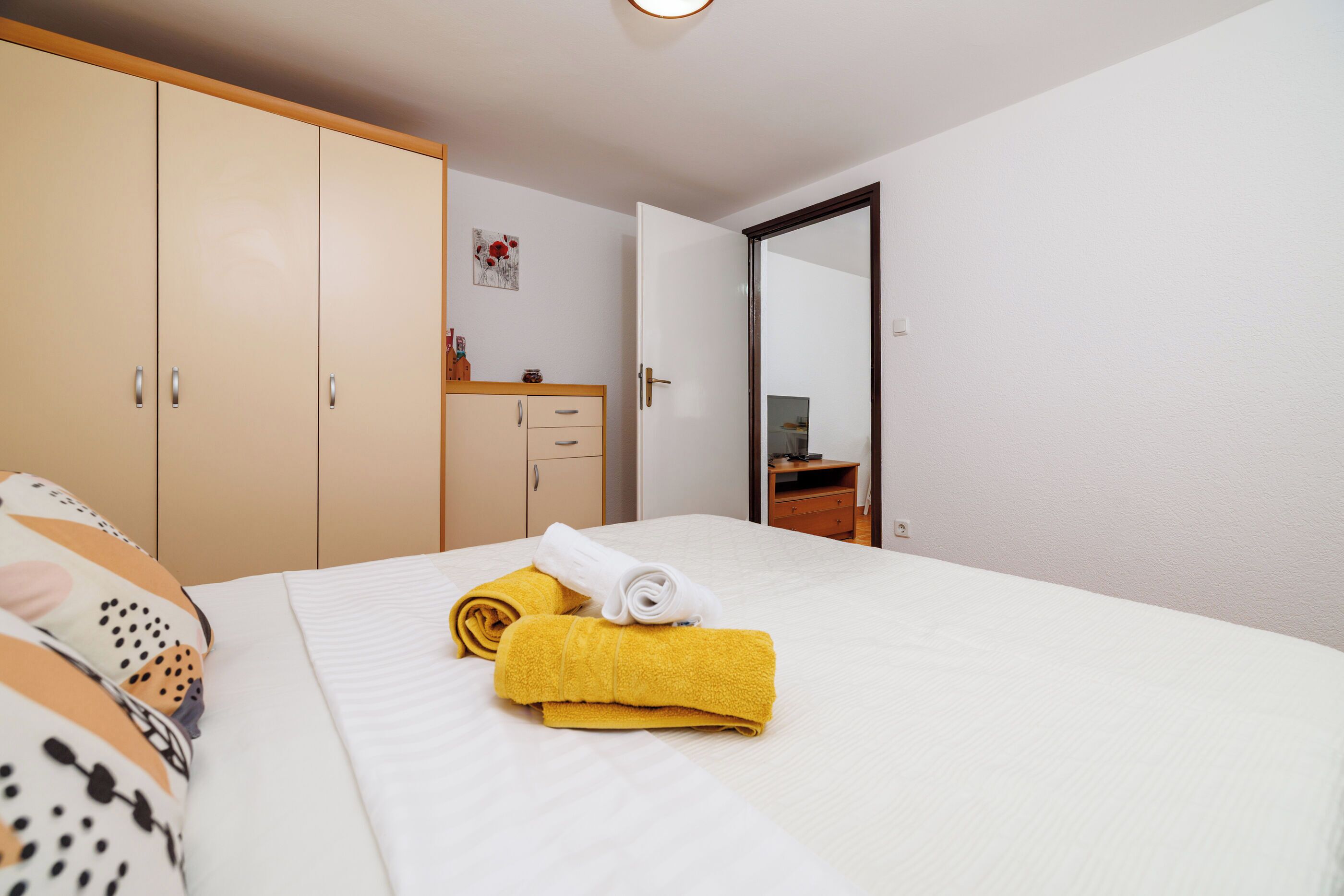 Una habitación de hotel con cama, armario, espejo y un pequeño escritorio con silla.