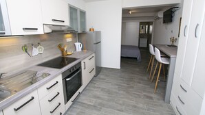 Een moderne keuken met witte kasten, een ingebouwde oven en een eetgedeelte met witte stoelen.