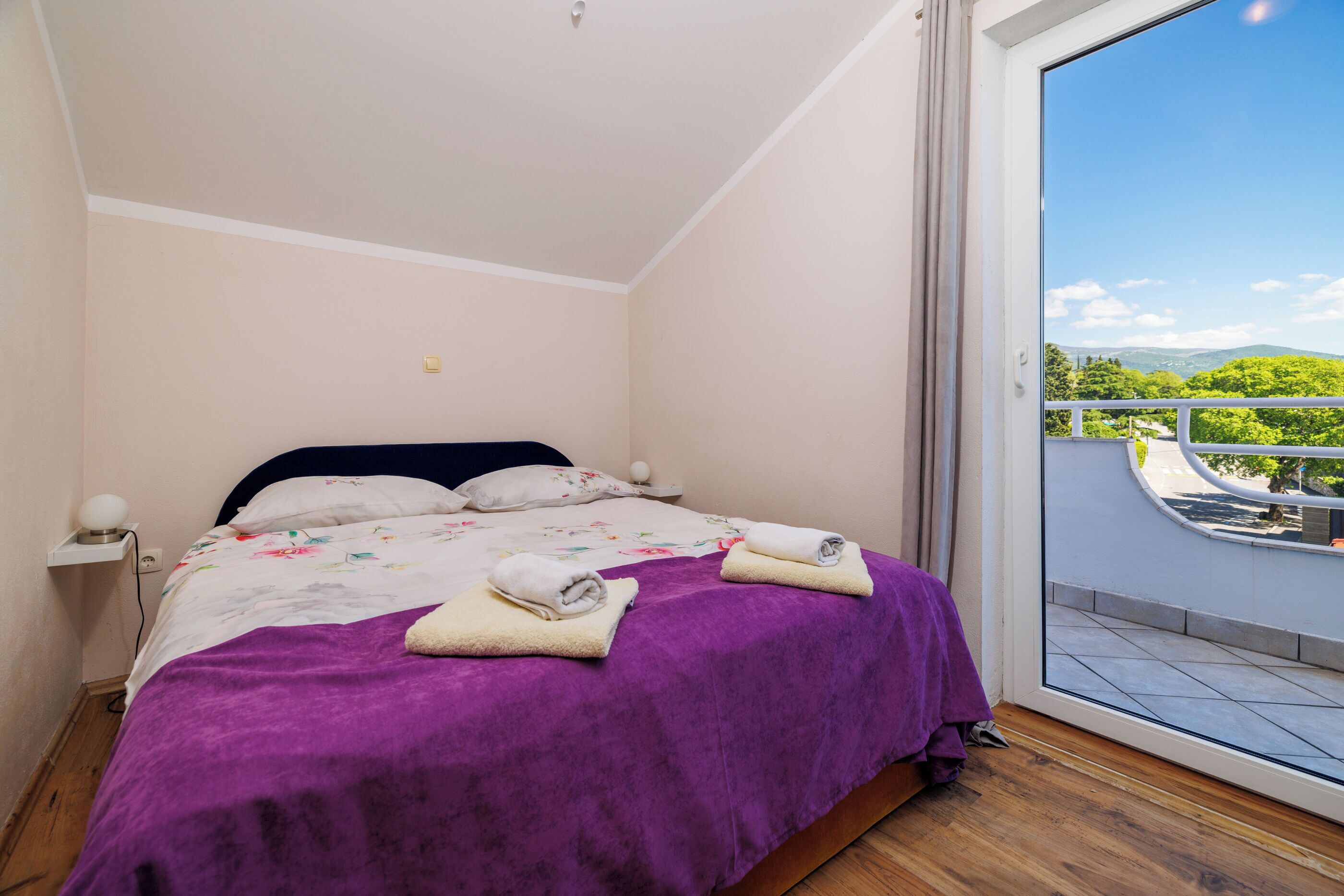 Une chambre à coucher avec un lit, une couvre-lit violette et des serviettes.