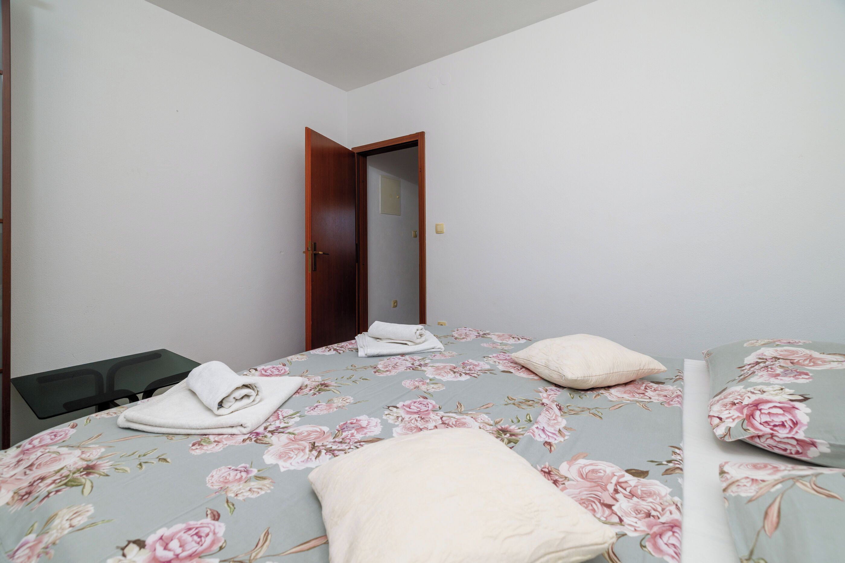 Un dormitorio con cama, mesita de noche, puerta y espejo.