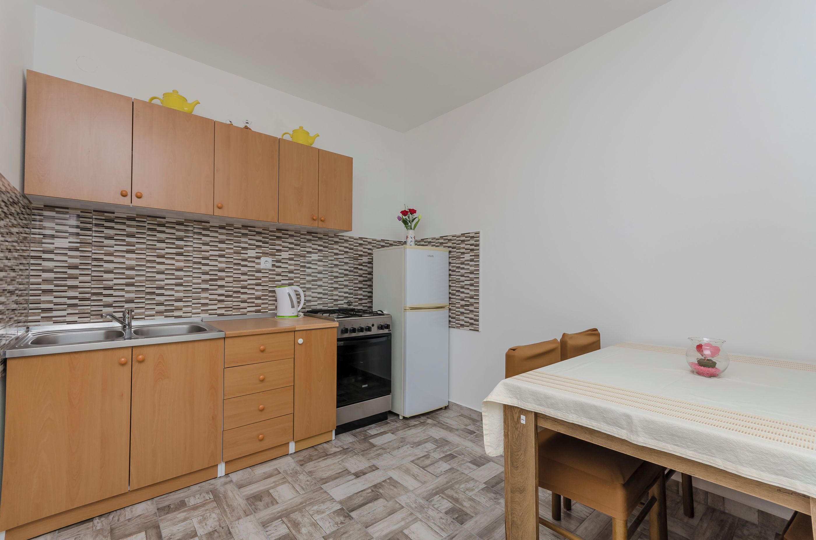 Una cocina compacta con armarios de madera, un refrigerador blanco, una estufa y un lavamanos.