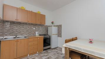 Una cocina compacta con armarios de madera, un refrigerador blanco, una estufa y un lavamanos.