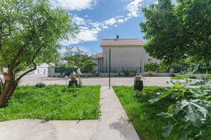 A residential area with a paved pathway leading to a house with a red-tiled roof. - Apartments Mila II (Tribunj)