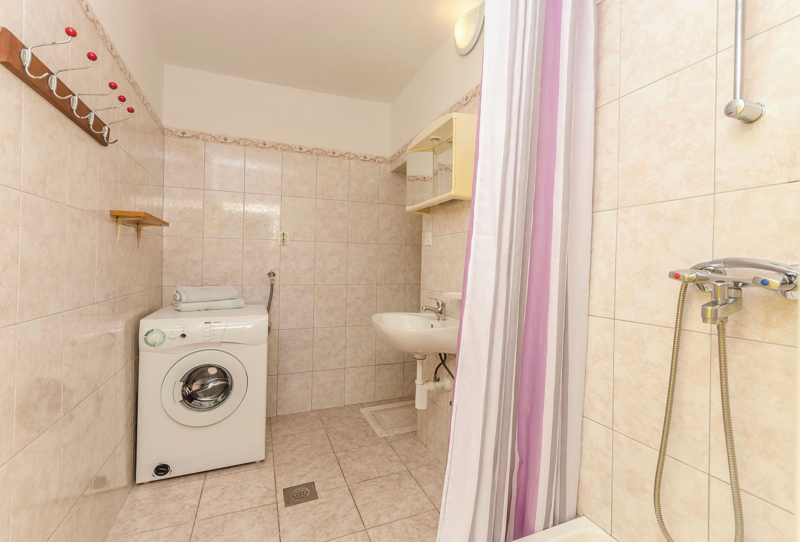 Un bany compacte amb rentadora, un lavabo i una dutxa.