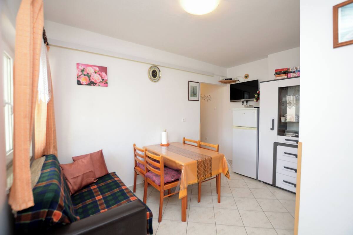 Un espace de vie compact comprenant un canapé, une table à manger et un coin cuisine.