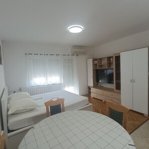 Une chambre à coucher comprenant un lit, un bureau, une chaise, un téléviseur et une armoire.