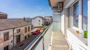 A balcony with a clear view of the street below, featuring a mix of residential buildings and parked cars. - Apartments Ivana (Crikvenica)