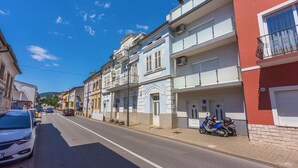 A street with parked cars and a scooter, buildings with balconies, and a clear blue sky. - Apartments Ivana (Crikvenica)