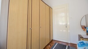 A room with a wooden wardrobe, a white door, a small bedside table, and a round mirror. - Apartments Josip by the sea (Novi Vinodolski)