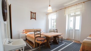 A bedroom with a bed, bedside table, chair, and a small table. - Apartments Josip by the sea (Novi Vinodolski)