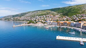 A coastal town with a marina, buildings with orange roofs, and a lighthouse.