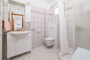 Une salle de bain avec un lavabo blanc, des toilettes et un rideau de douche.