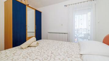 A bedroom with a bed, a wardrobe, a radiator, and a window with curtains.