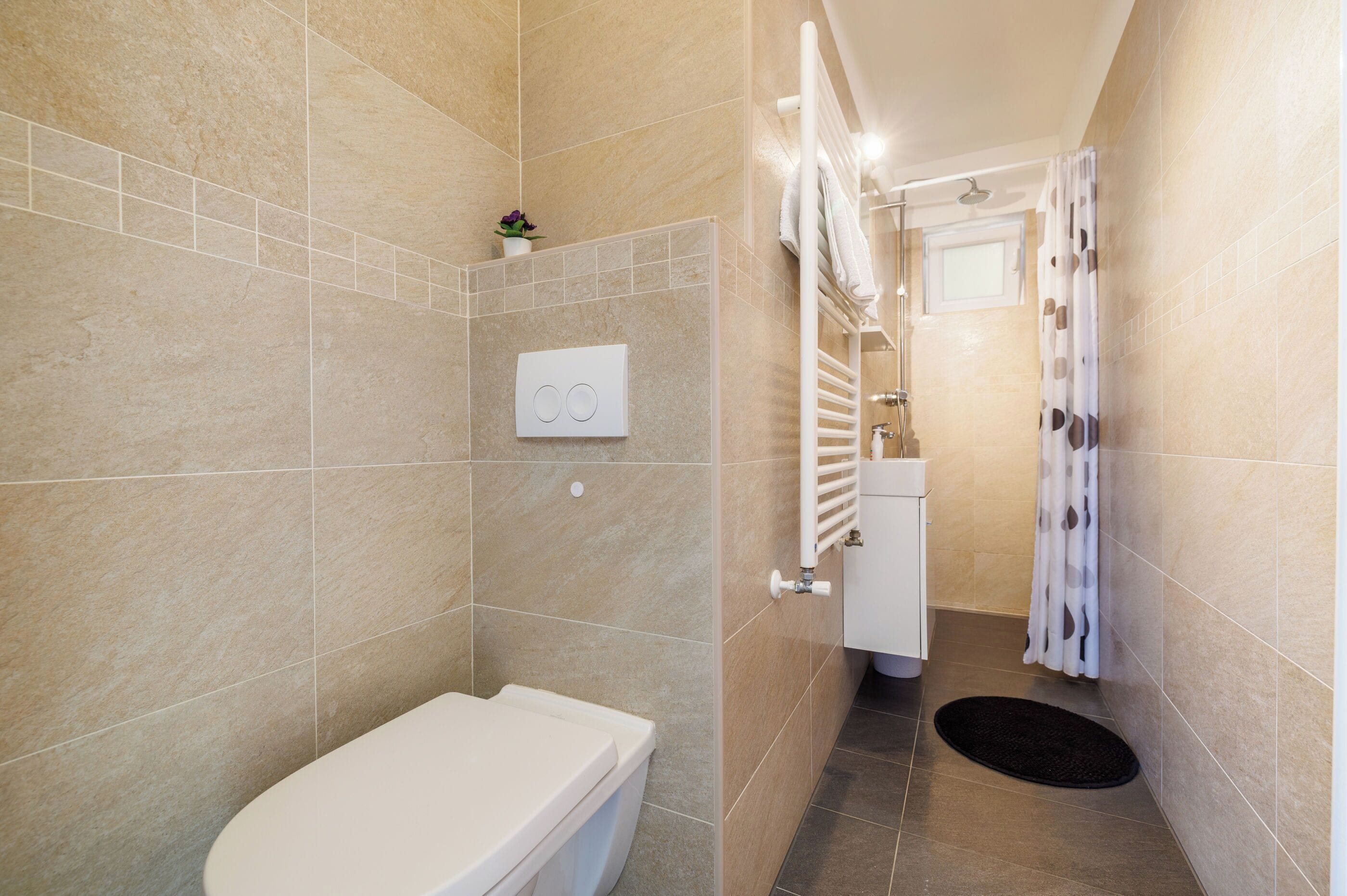 Un baño moderno con inodoro, ducha y un ventanal.