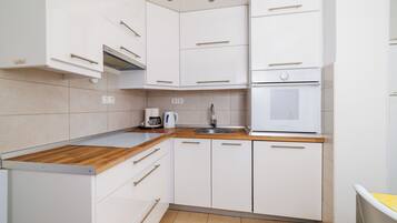 A modern kitchen with white cabinets, a wooden countertop, a built-in oven, and a sink.