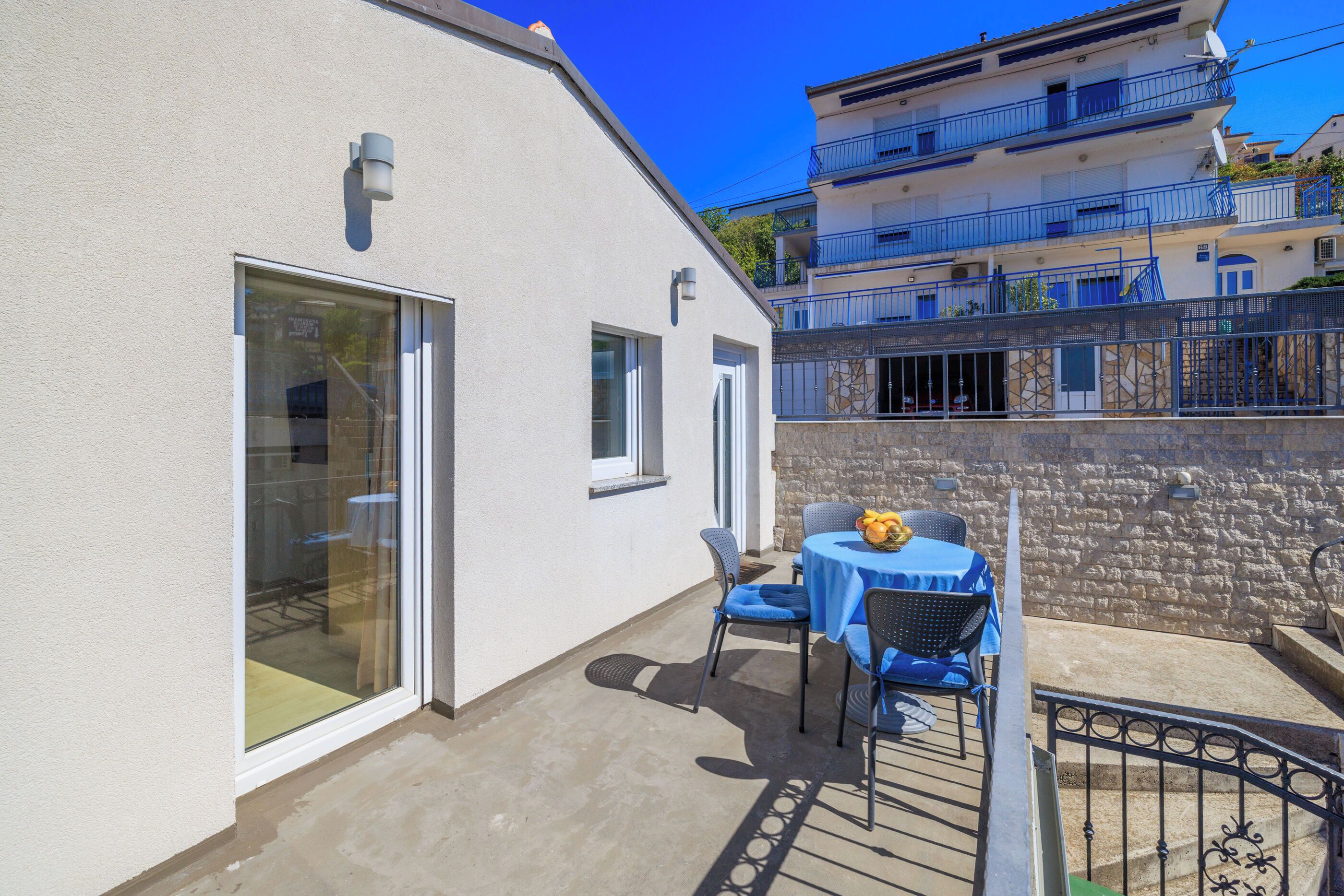 A balcony with a table and chairs, a glass door, and a stone wall.
