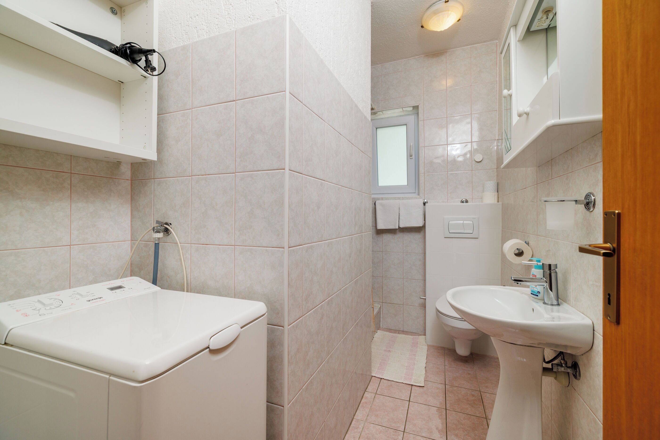 Ein Badezimmer mit Waschmaschine, Waschbecken und Toilette.