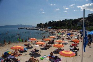 Una playa con numerosos paraguas y gente tomando el sol.