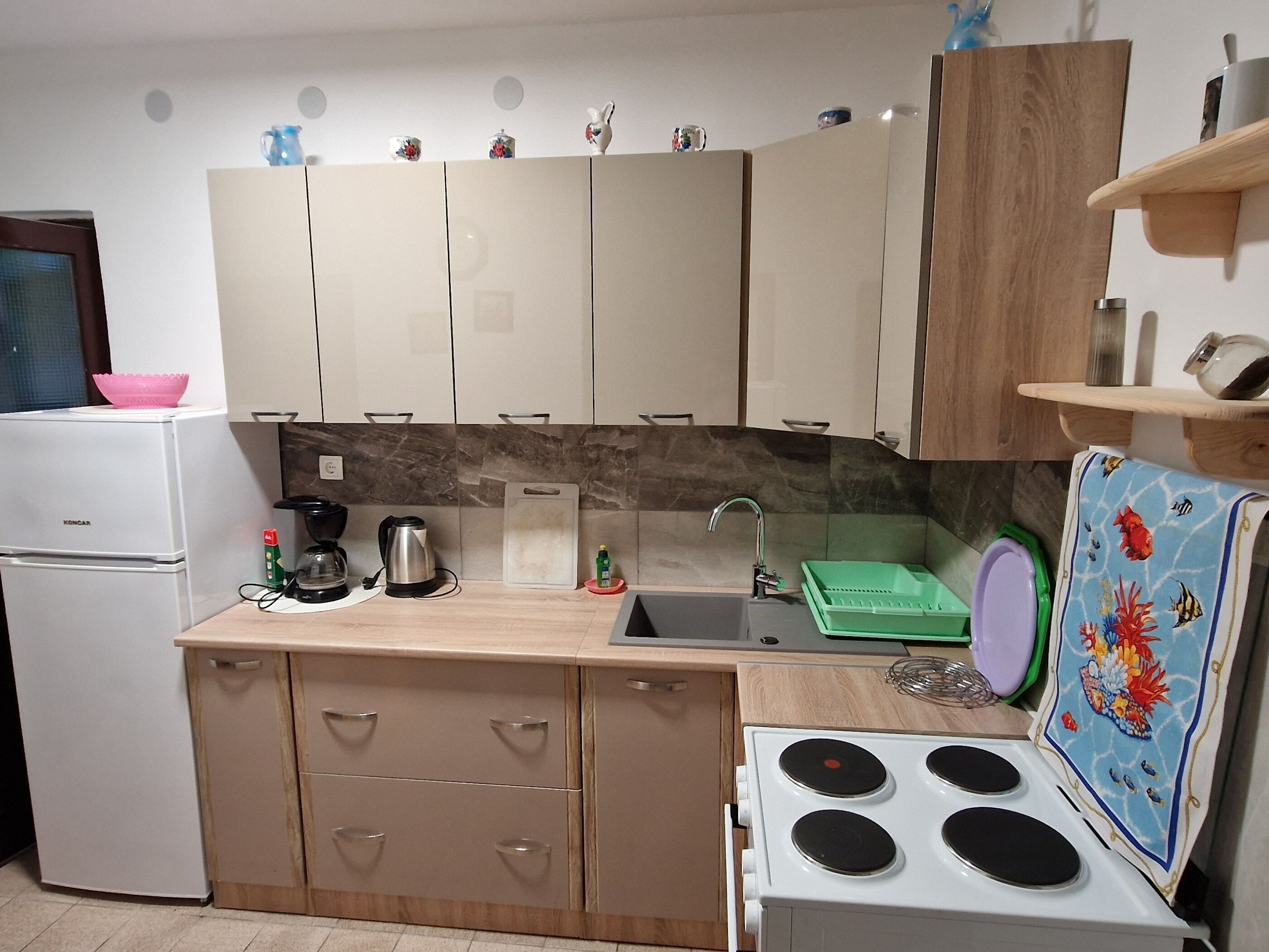 Una cocina compacta equipada con refrigerador, estufa, pileta y alacenas.
