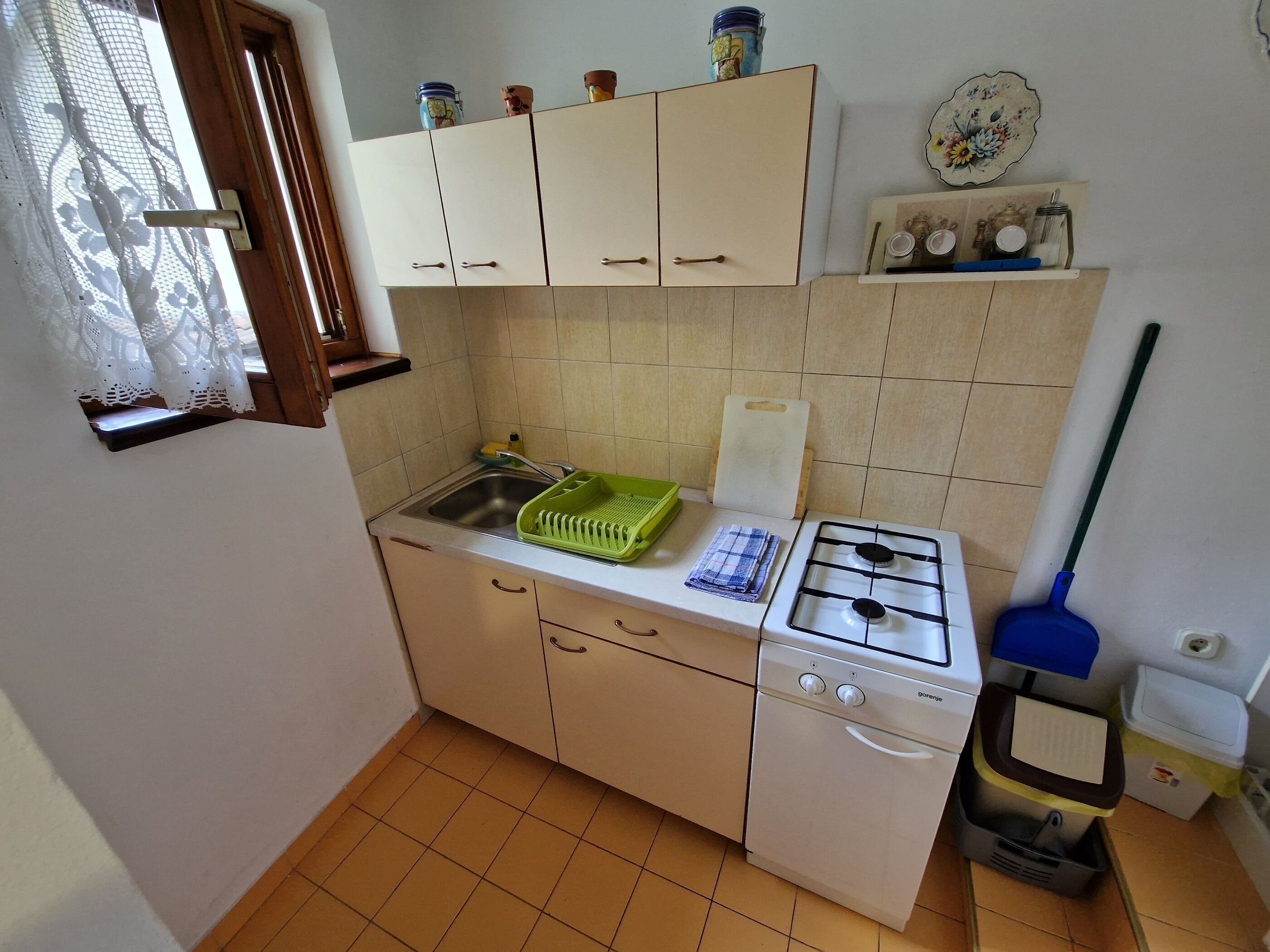 A compact kitchen with a gas stove, sink, and cabinets.