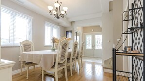 A dining area with a table set for four, surrounded by chairs, a chandelier, and a window with blinds. - Apartment Canada Dream Vacation (Srima)