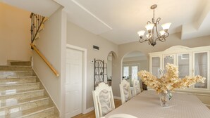 A dining area with a long table, white chairs, a chandelier, and a staircase. - Apartment Canada Dream Vacation (Srima)