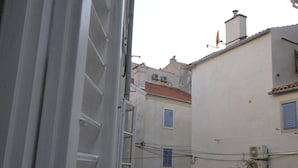 Una stretta via fiancheggiata da edifici dall'architettura tradizionale, con comignoli e condizionatori d'aria ben visibili.