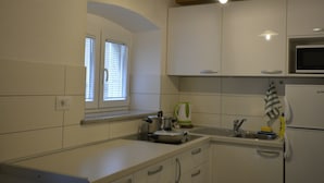 Una cucina con mobili bianchi, un forno a microonde, un bollitore e un lavandino.