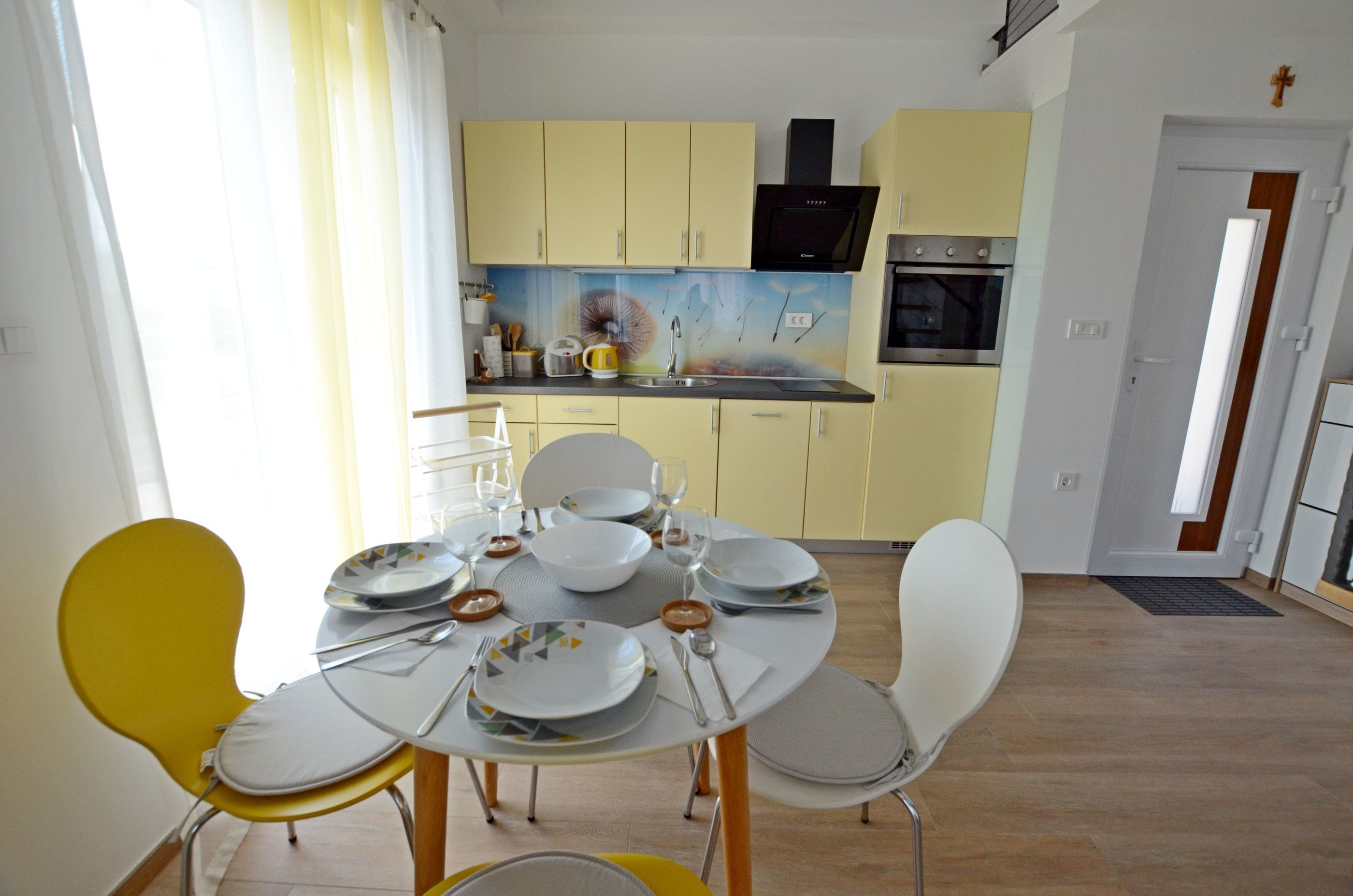 Un comedor con una mesa dispuesta para cuatro personas, sillas amarillas y una mesa de comedor amarilla.