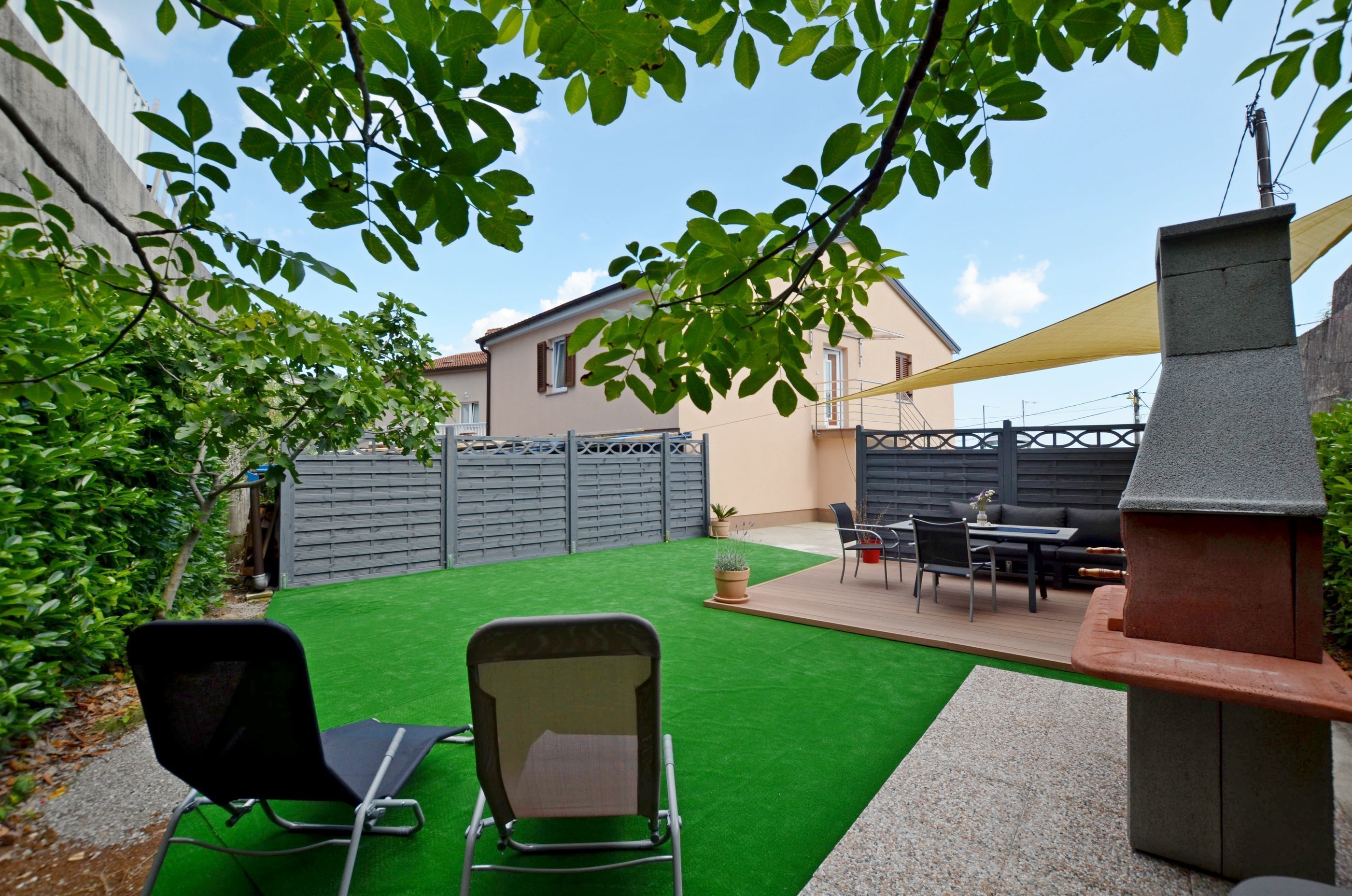 Un espace extérieur aménagé avec du gazon synthétique, un barbecue et du mobilier de jardin.
